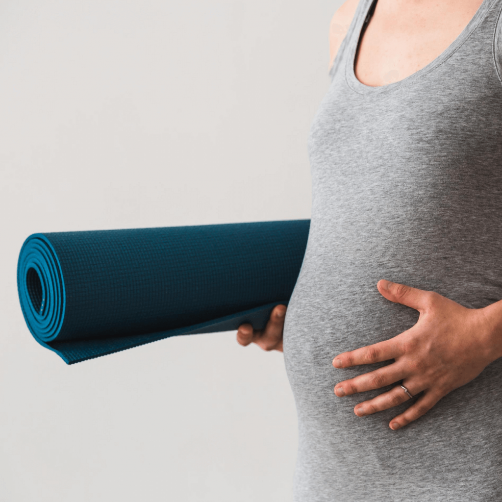Schwangere mit Yogamatte und Babybauch